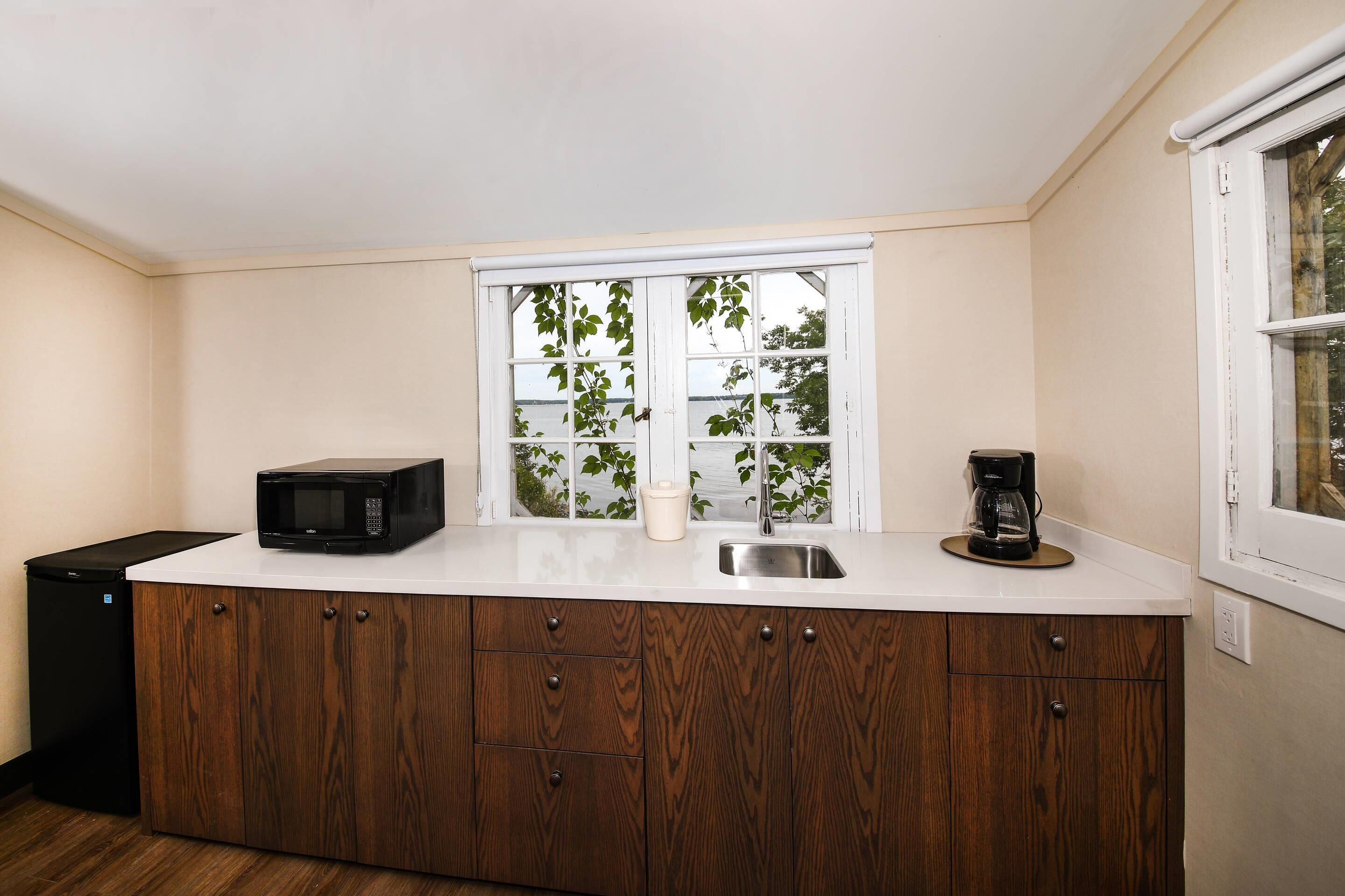 Eine kleine Küche mit einer Mikrowelle, einer Kaffeemaschine und einem Fenster mit Pflanzen.