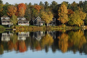 Une propriété au bord du lac comprenant plusieurs maisons, un quai et un paysage automnal aux couleurs flamboyantes.