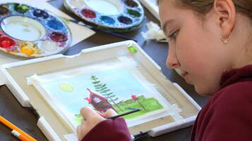 A person painting a landscape with a house and trees on a canvas.