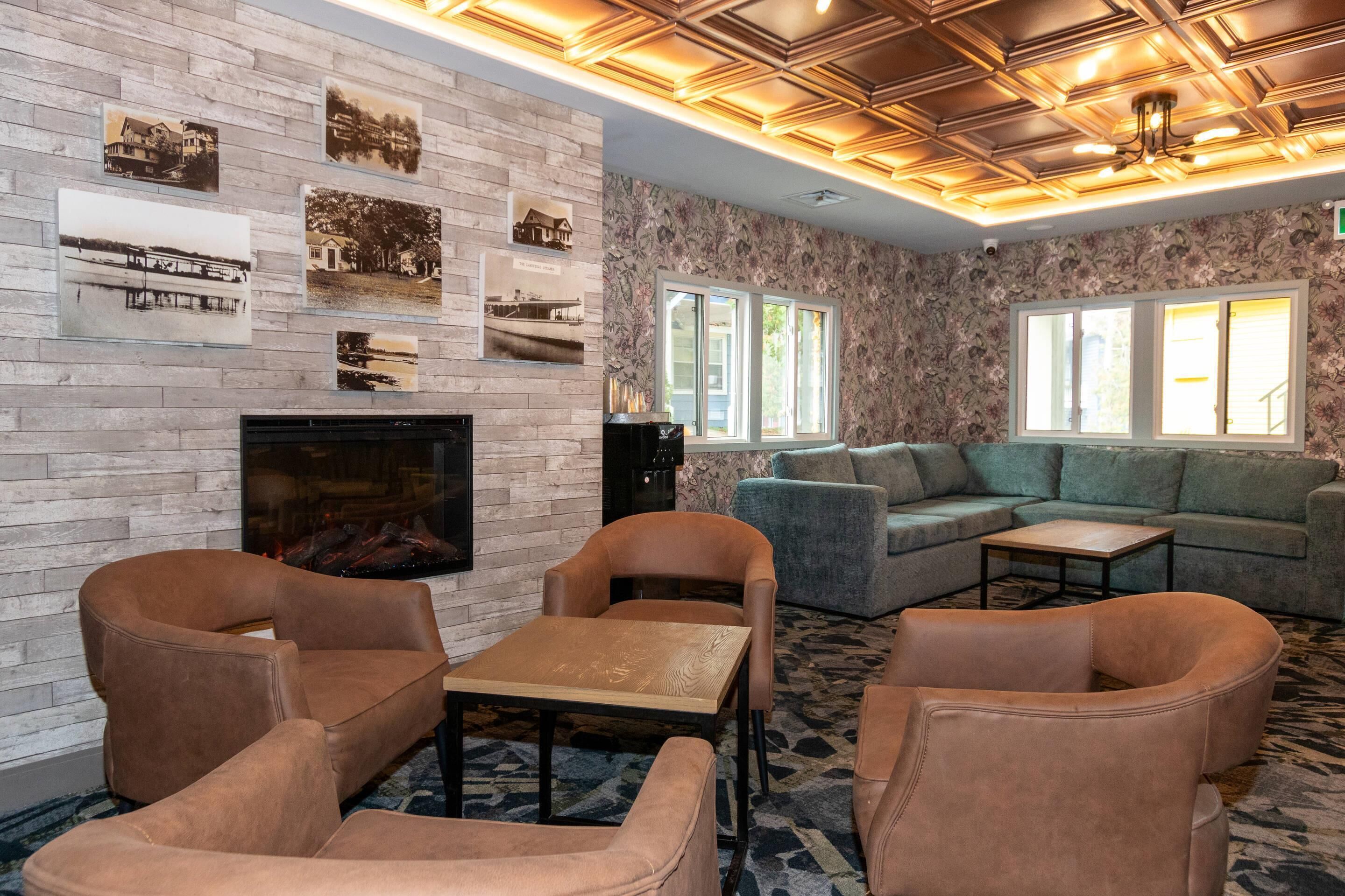 A cozy living room with a fireplace, comfortable seating, and a patterned carpet.