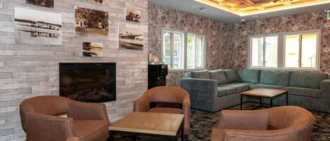 A cozy living room with a fireplace, comfortable seating, and a patterned carpet.