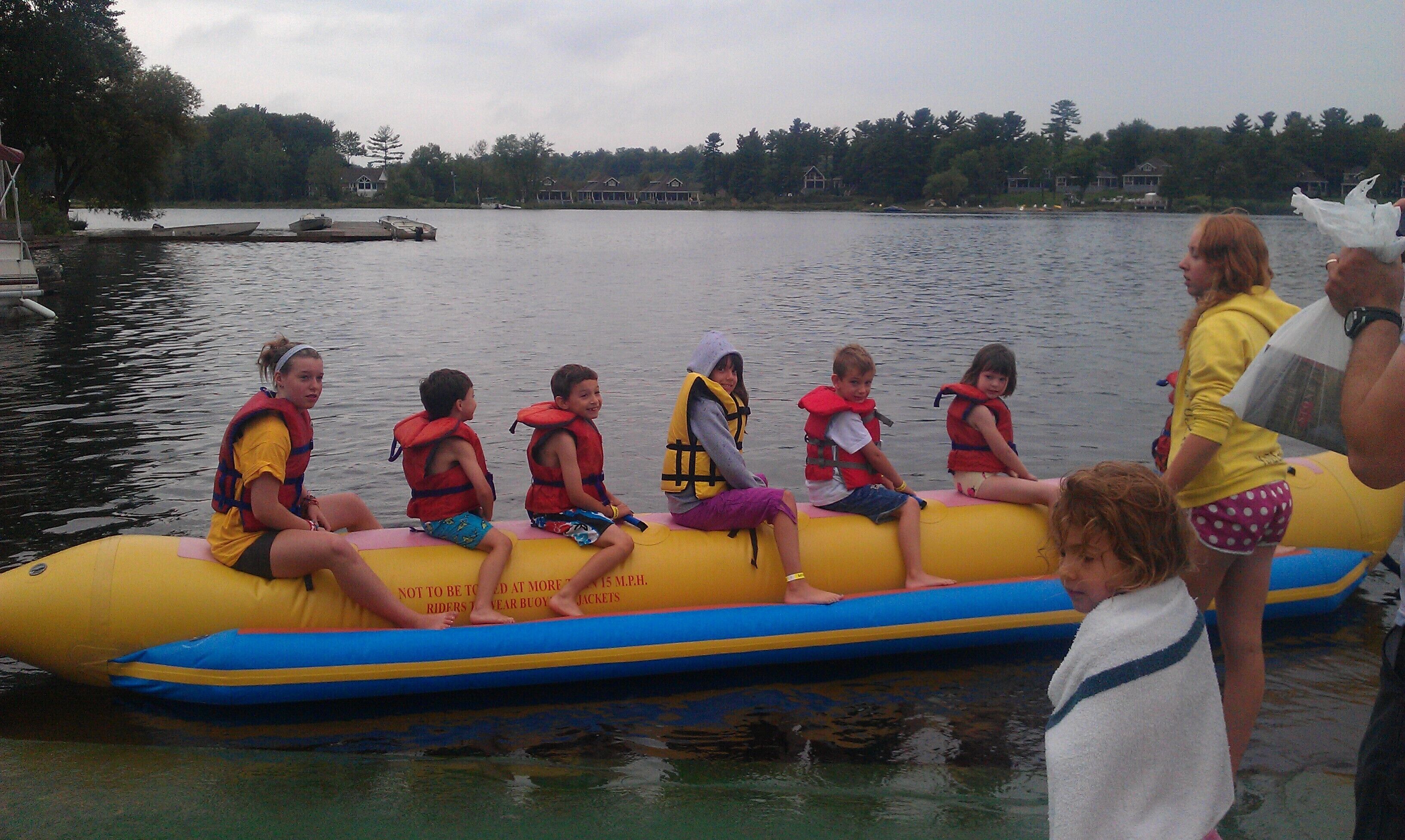 A group of people on a yellow inflatable raft with life jackets, floating on a body of water.