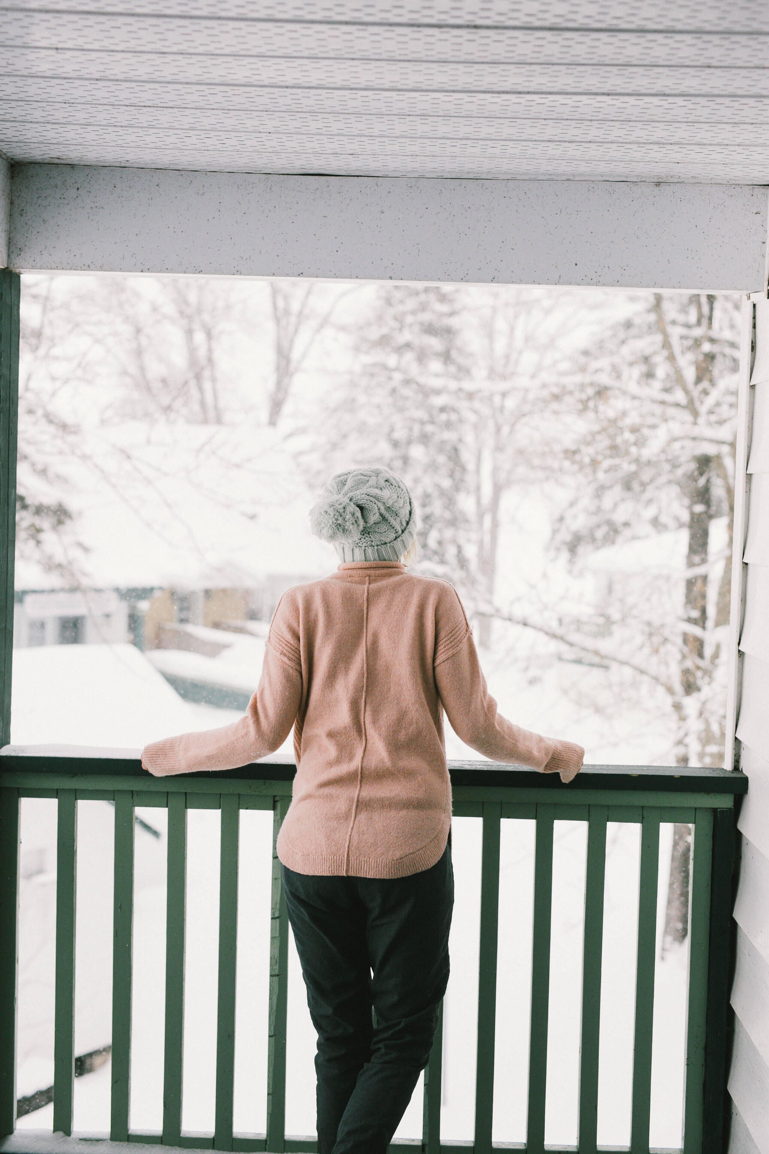 A person standing on a balcony with a view of a snowy landscape.