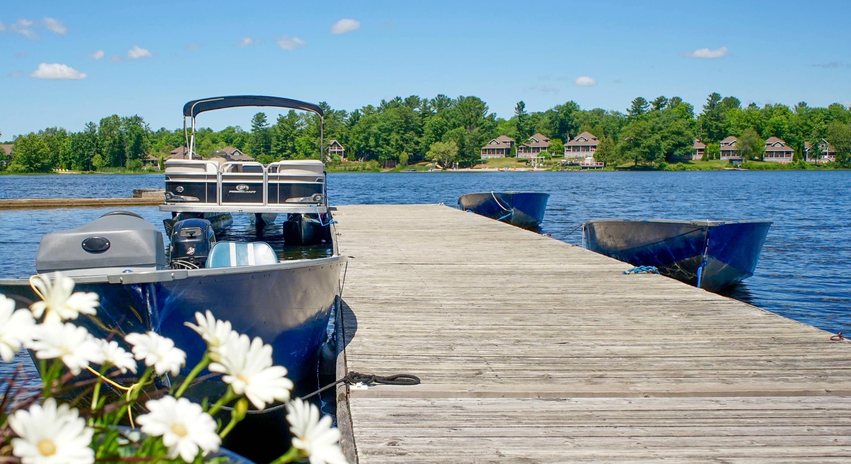 A wooden dock extending into a lake with boats moored at the end.