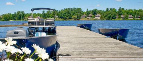 A wooden dock extending into a lake with boats moored at the end.