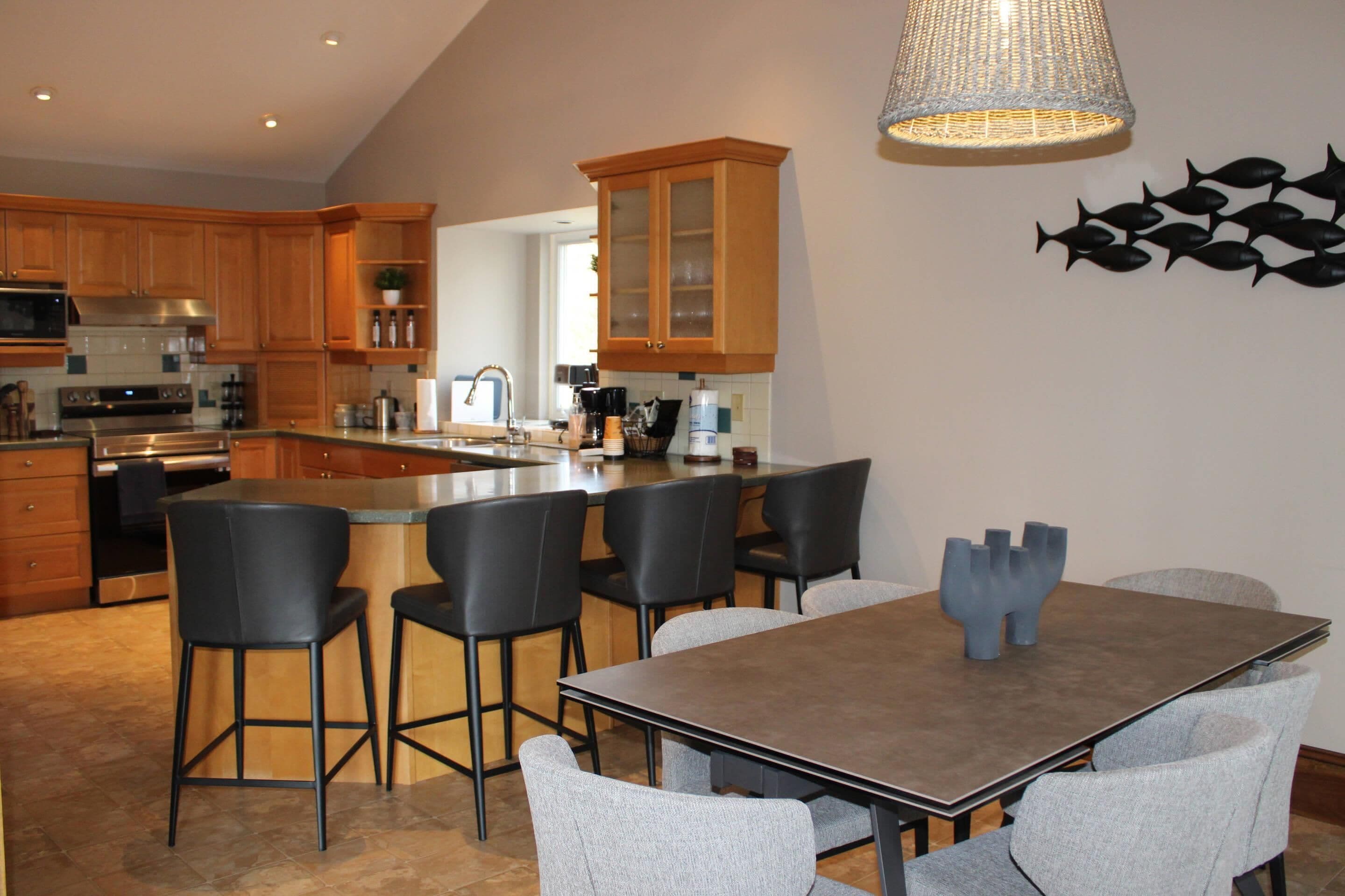 A modern kitchen with wooden cabinets, a central island, and a dining area with a table and chairs.