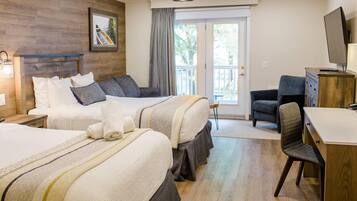 A hotel room with two beds, a desk, a chair, a television, and a balcony.