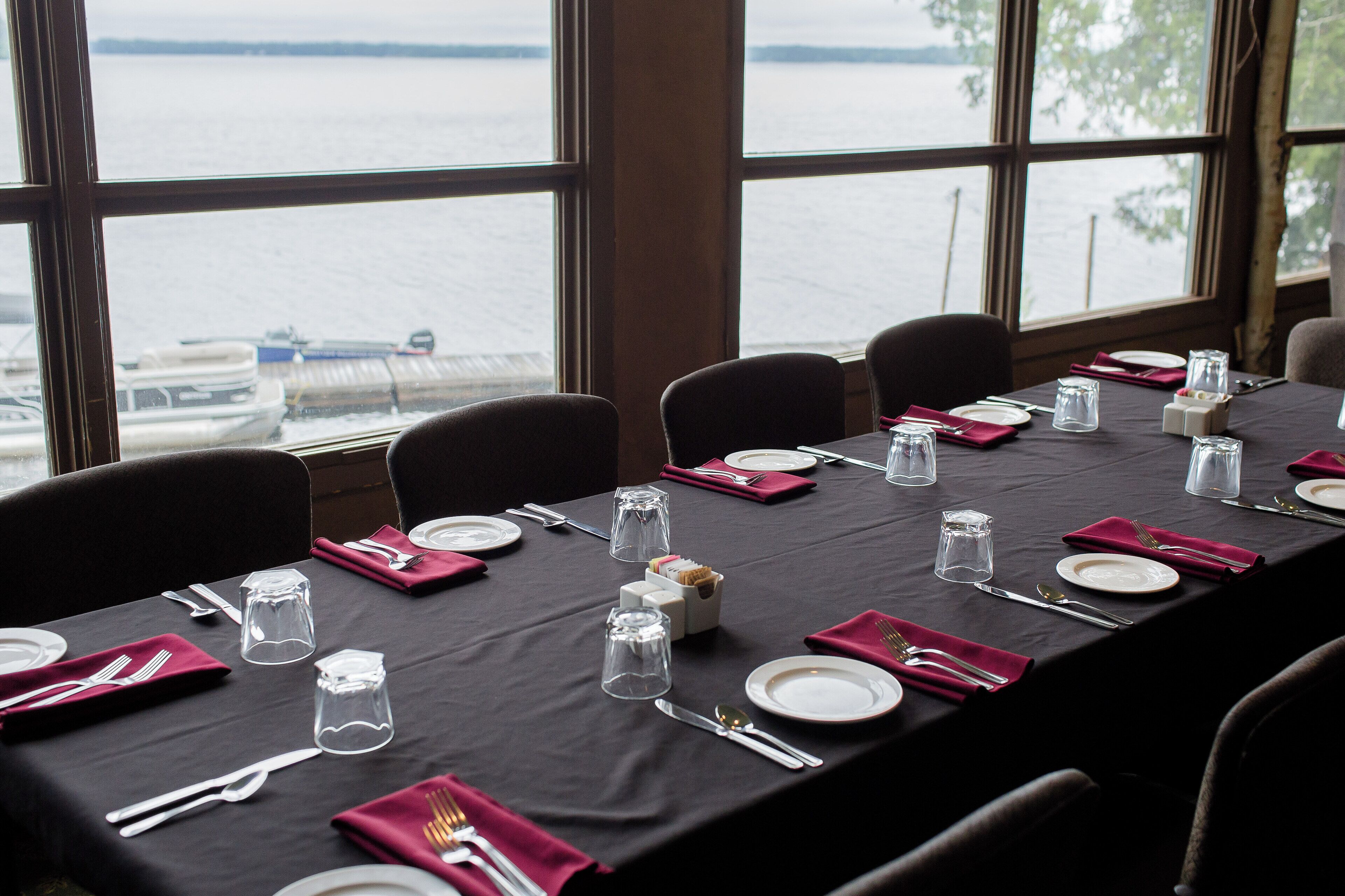 A table set for dining with a view of the water and boats outside.