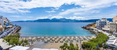 Ein Küstenhotel mit Sitzgelegenheiten im Freien, einem Strand und Bergblick.