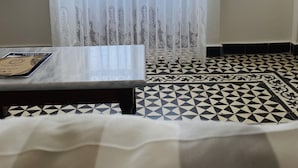 Une chambre avec un lit, une table, une télévision et une fenêtre avec des rideaux légers.