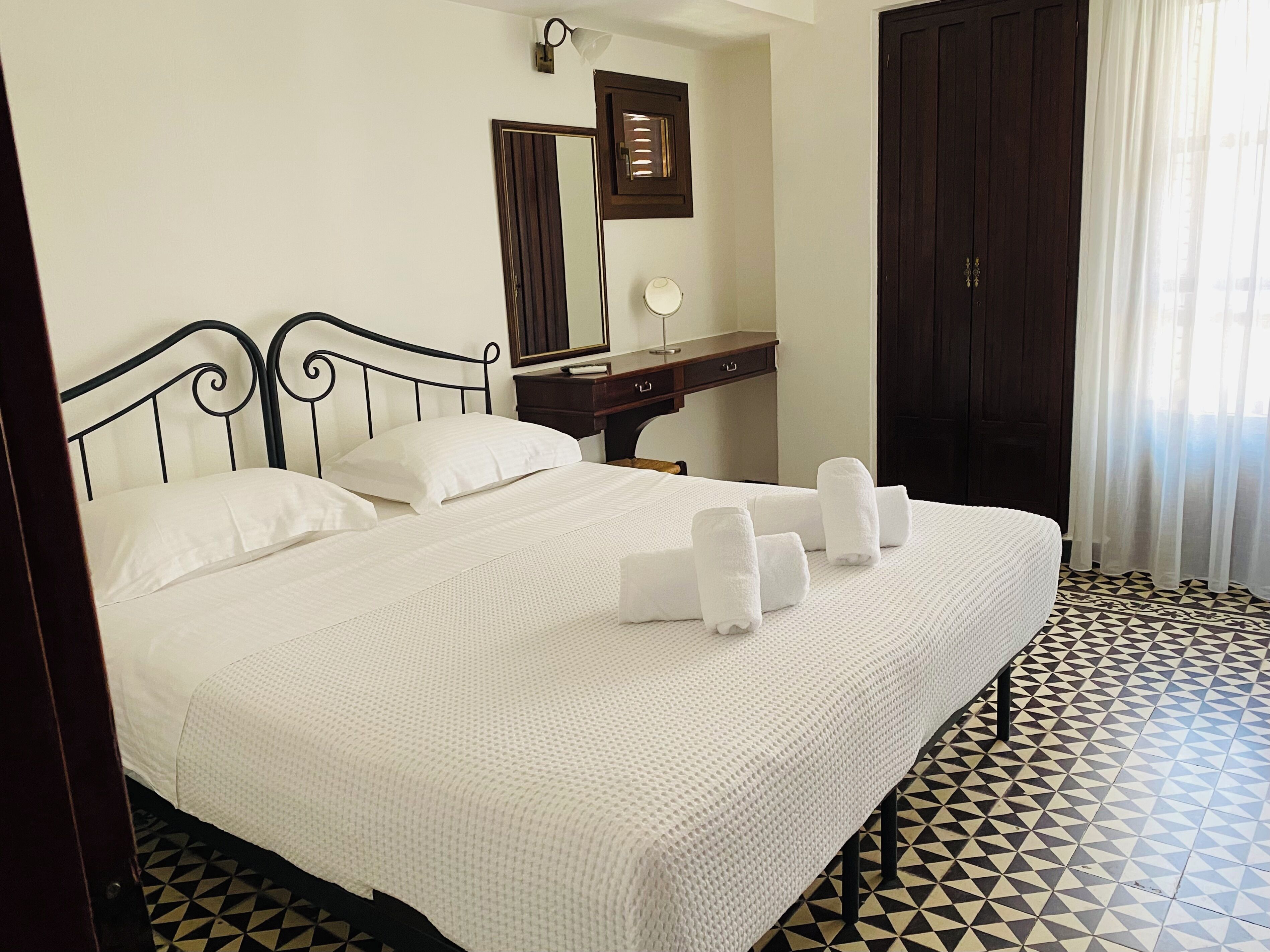 Une chambre d’hôtel comprenant un lit, une table de chevet, un miroir et une armoire.