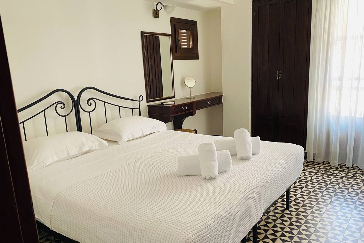 A hotel room with a bed, a bedside table, a mirror, and a wardrobe.