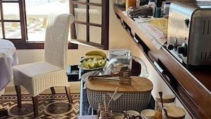 Un buffet de petit-déjeuner avec vue sur l’océan, une chaise en osier et un sol carrelé.