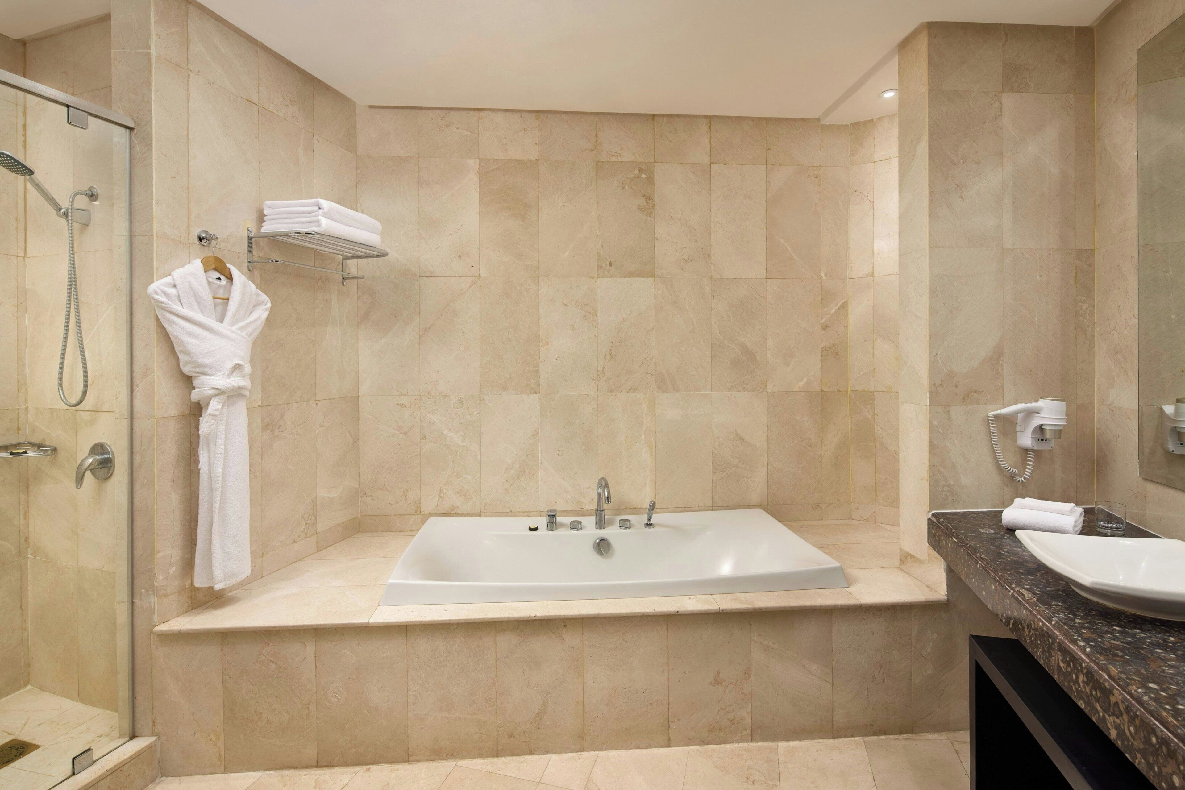 A modern bathroom with a large bathtub, a shower, and a vanity with a sink.