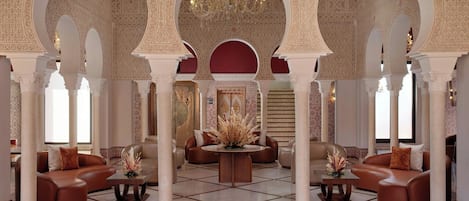 An interior with arches, a chandelier, and seating arrangements.