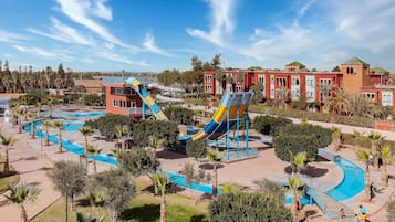 Relax by the resort's large pool, featuring slides and a water play structure, surrounded by palm trees and walkways.