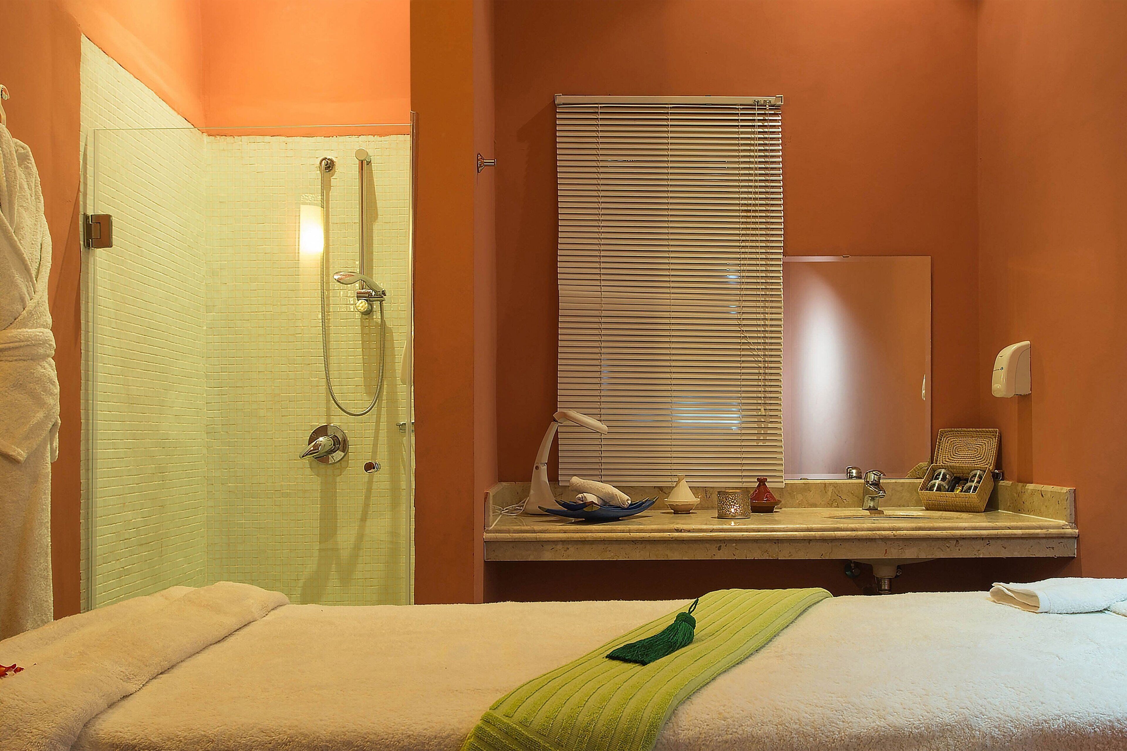 A hotel bathroom with a shower, sink, and mirror.