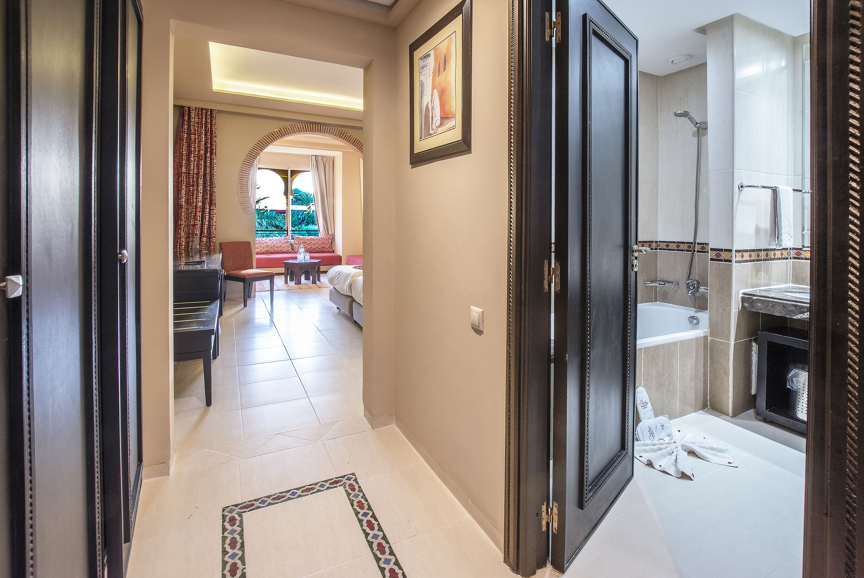 Pasillo de hotel que conduce a un baño con bañera y ducha.