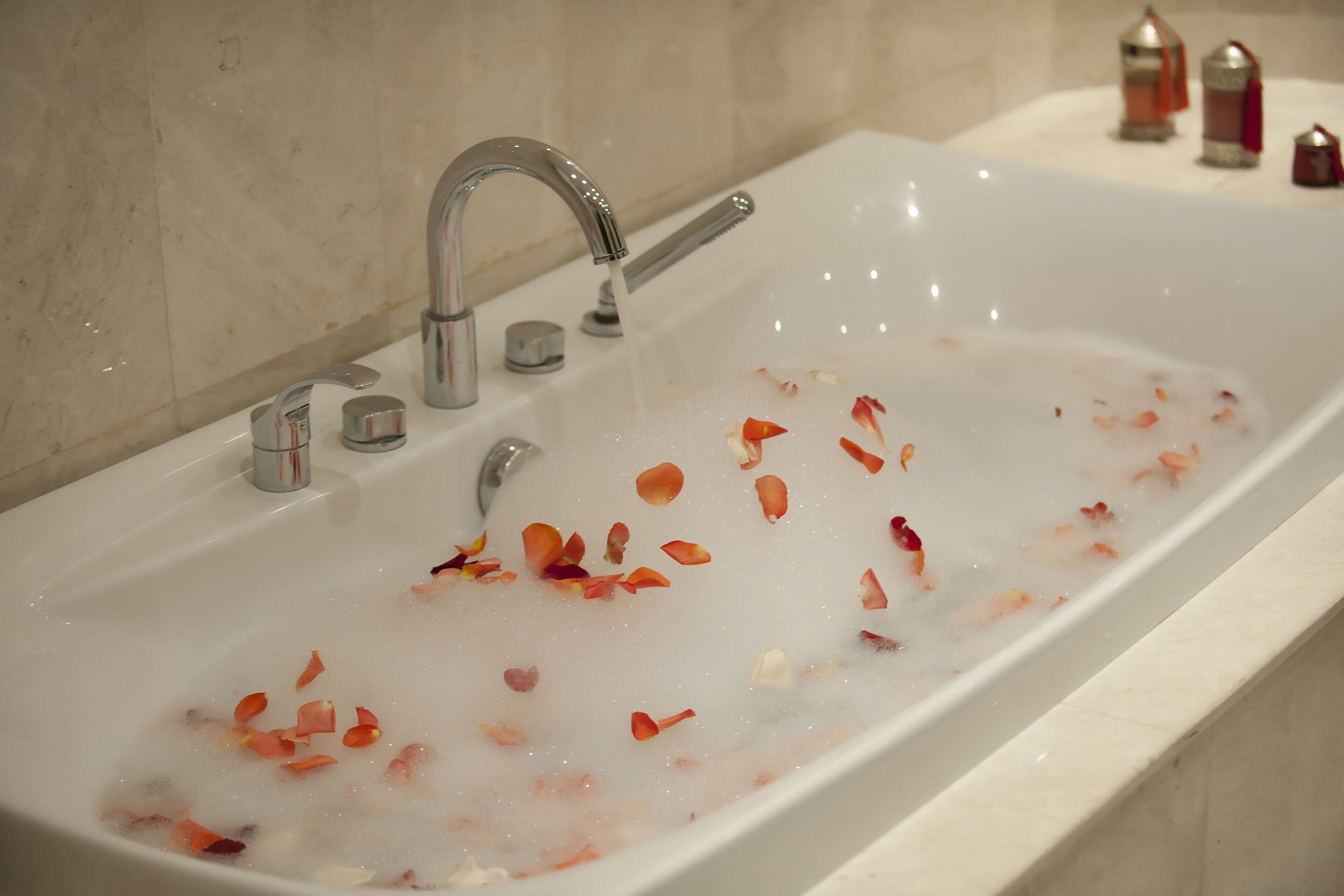 A bathroom with a bathtub filled with water and rose petals.