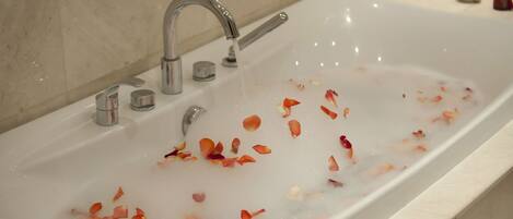 A bathroom with a bathtub filled with water and rose petals.