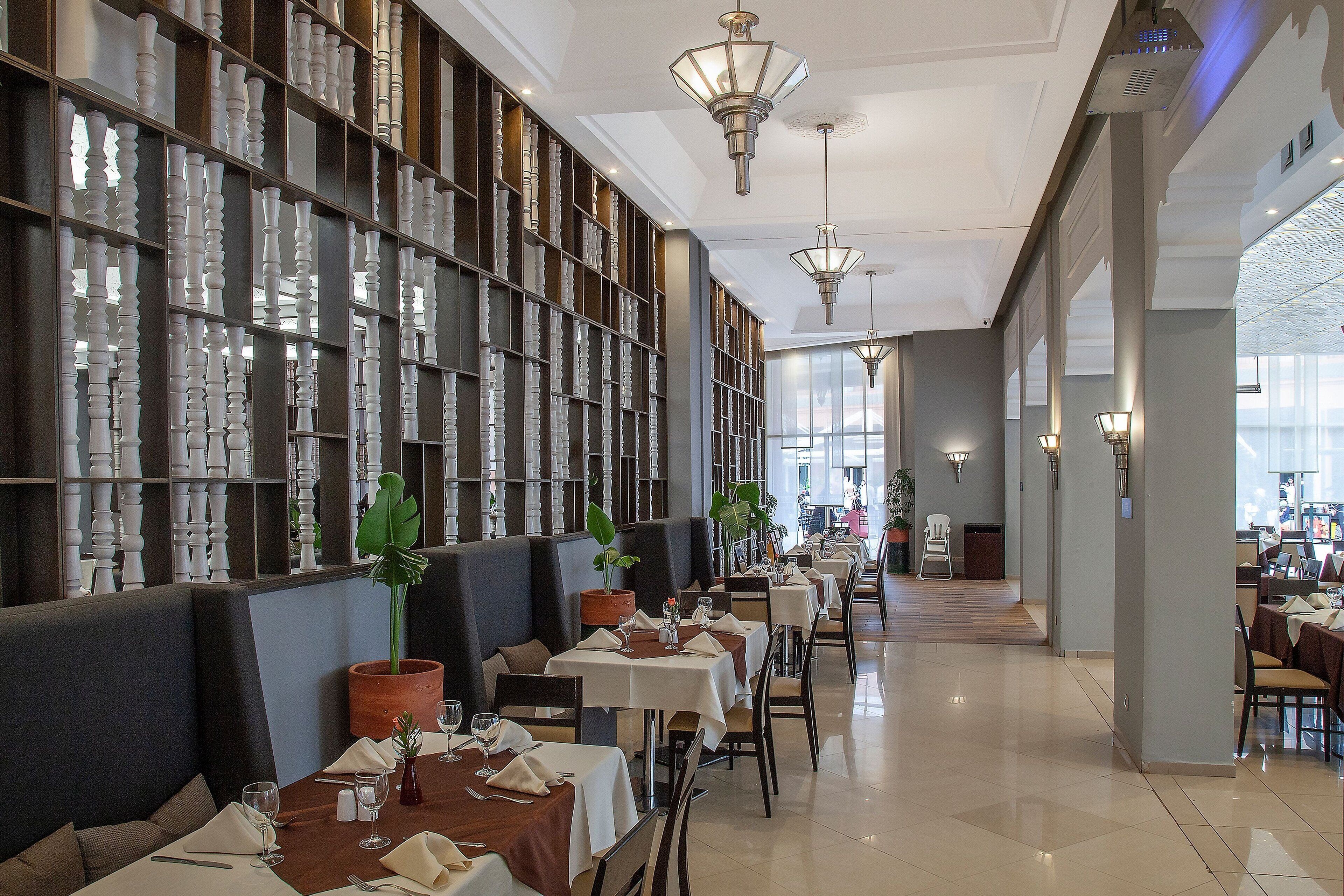Un restaurante con mesas largas, cabinas oscuras y una pared de jarrones decorativos.