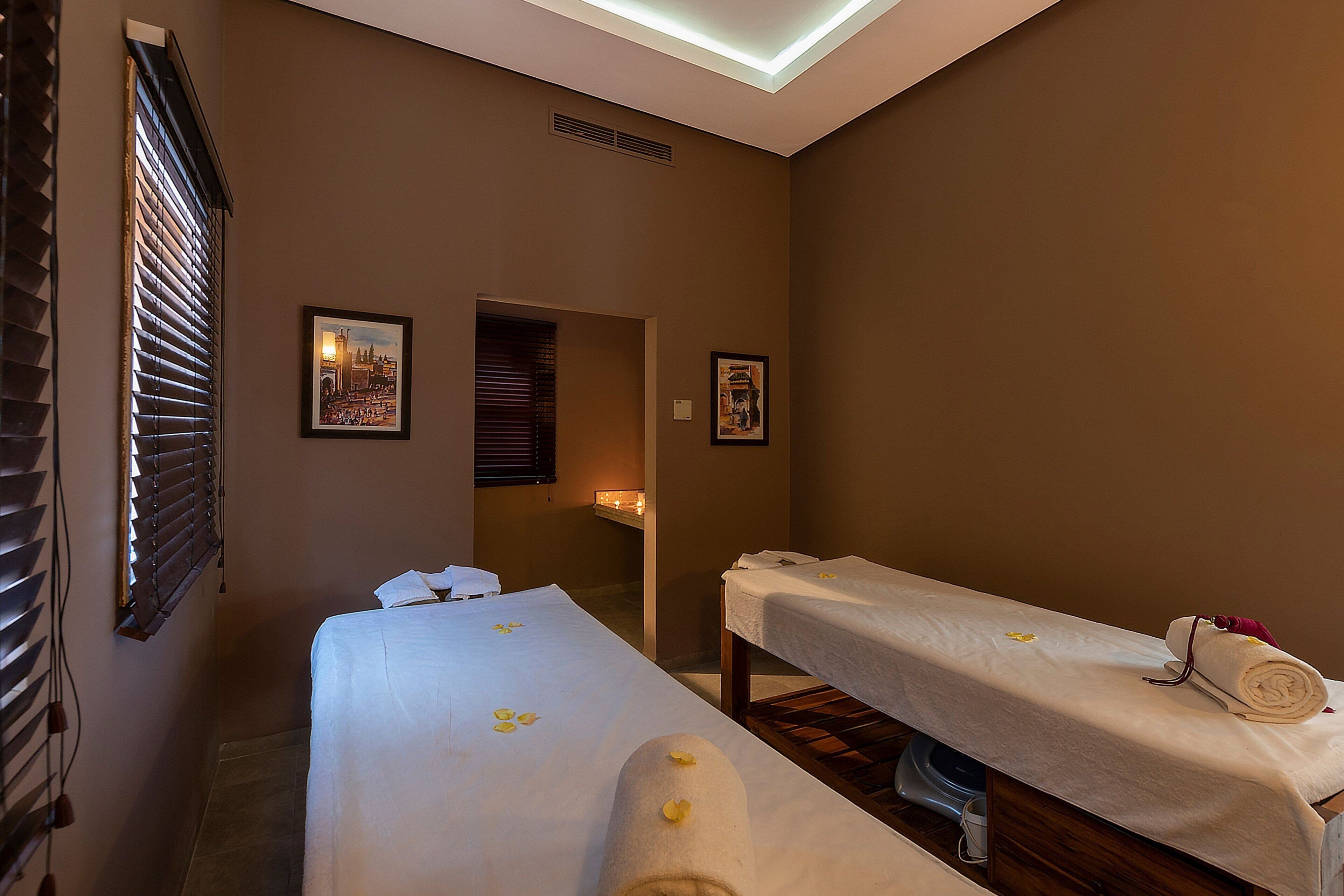 A spa room with two massage tables, each with a towel and a small decorative item.