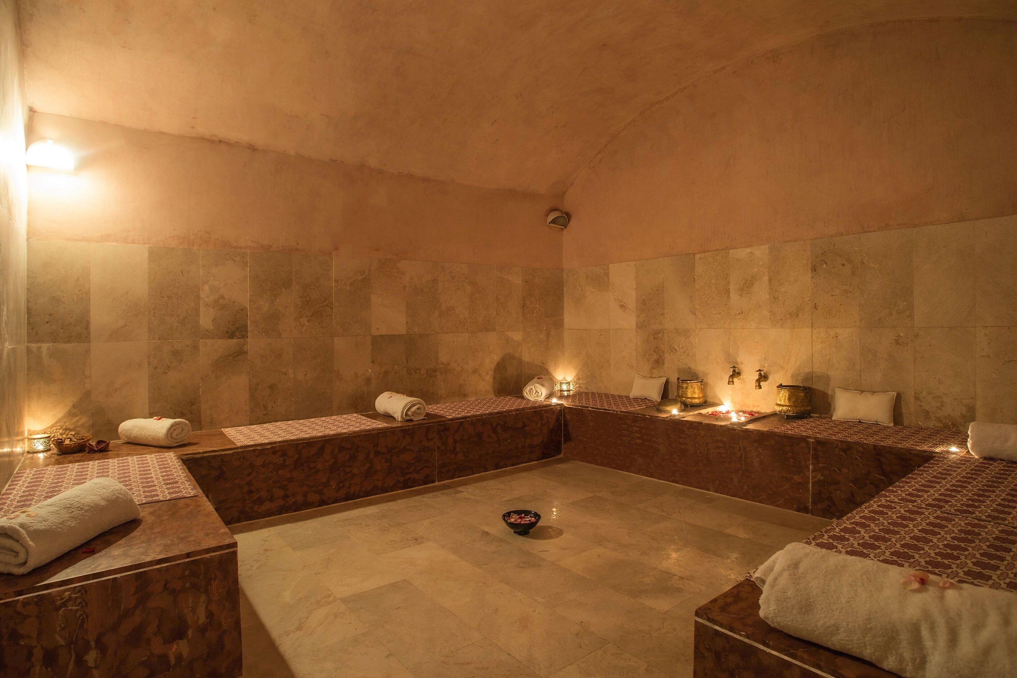 A spa room with a large bathtub, two smaller tubs, and a massage table.