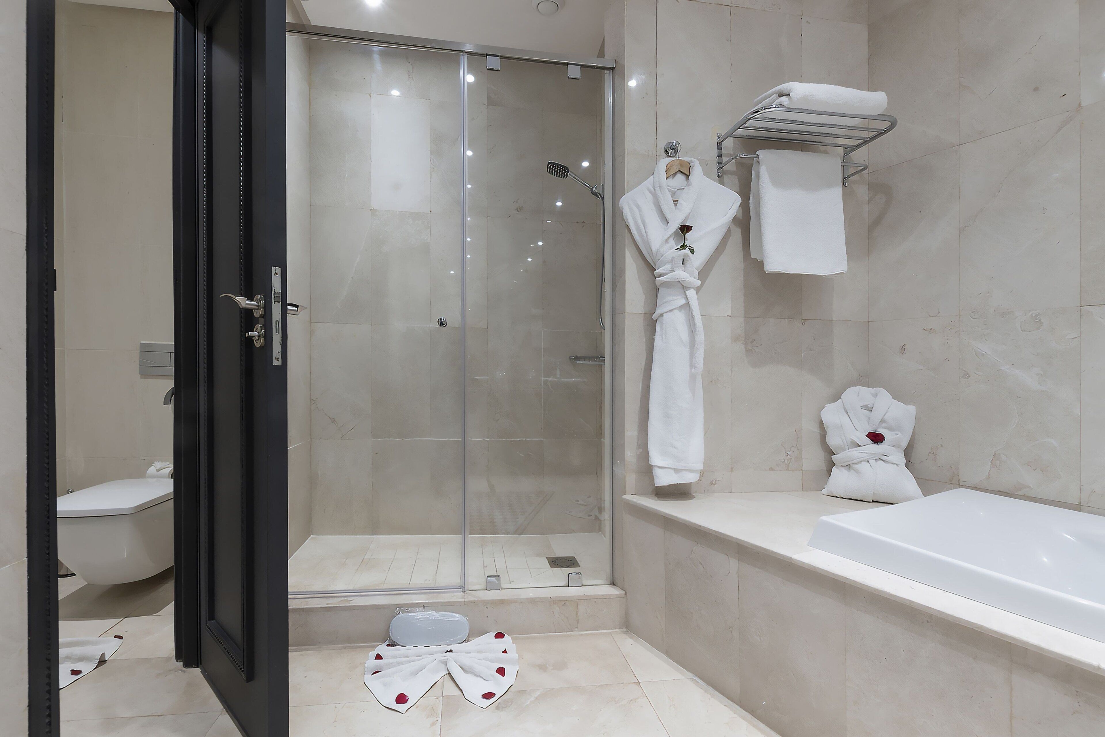 A modern bathroom with a glass-enclosed shower, a white bathtub, and a toilet.