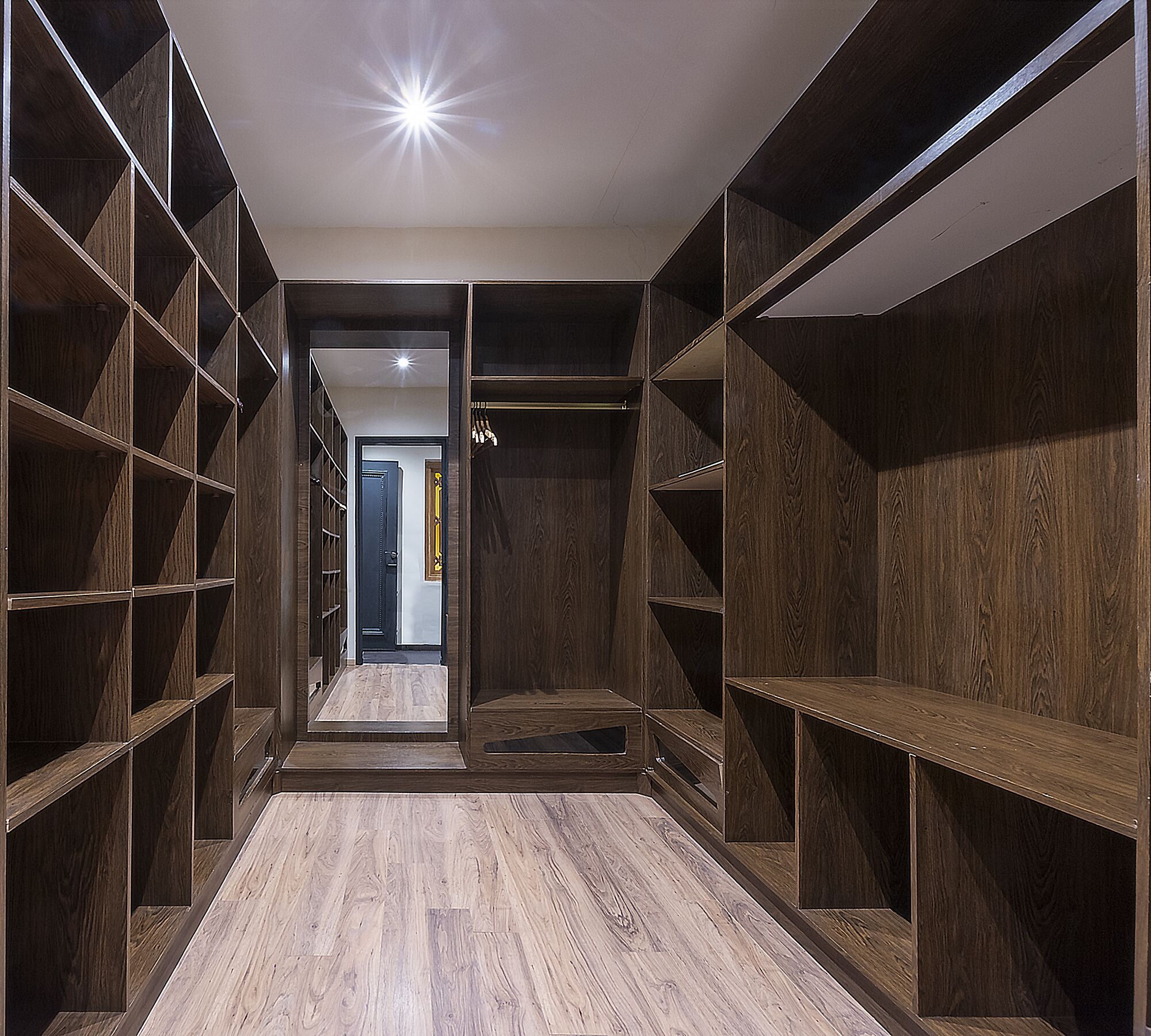 Un vestidor con estantes de madera y un pasillo central.