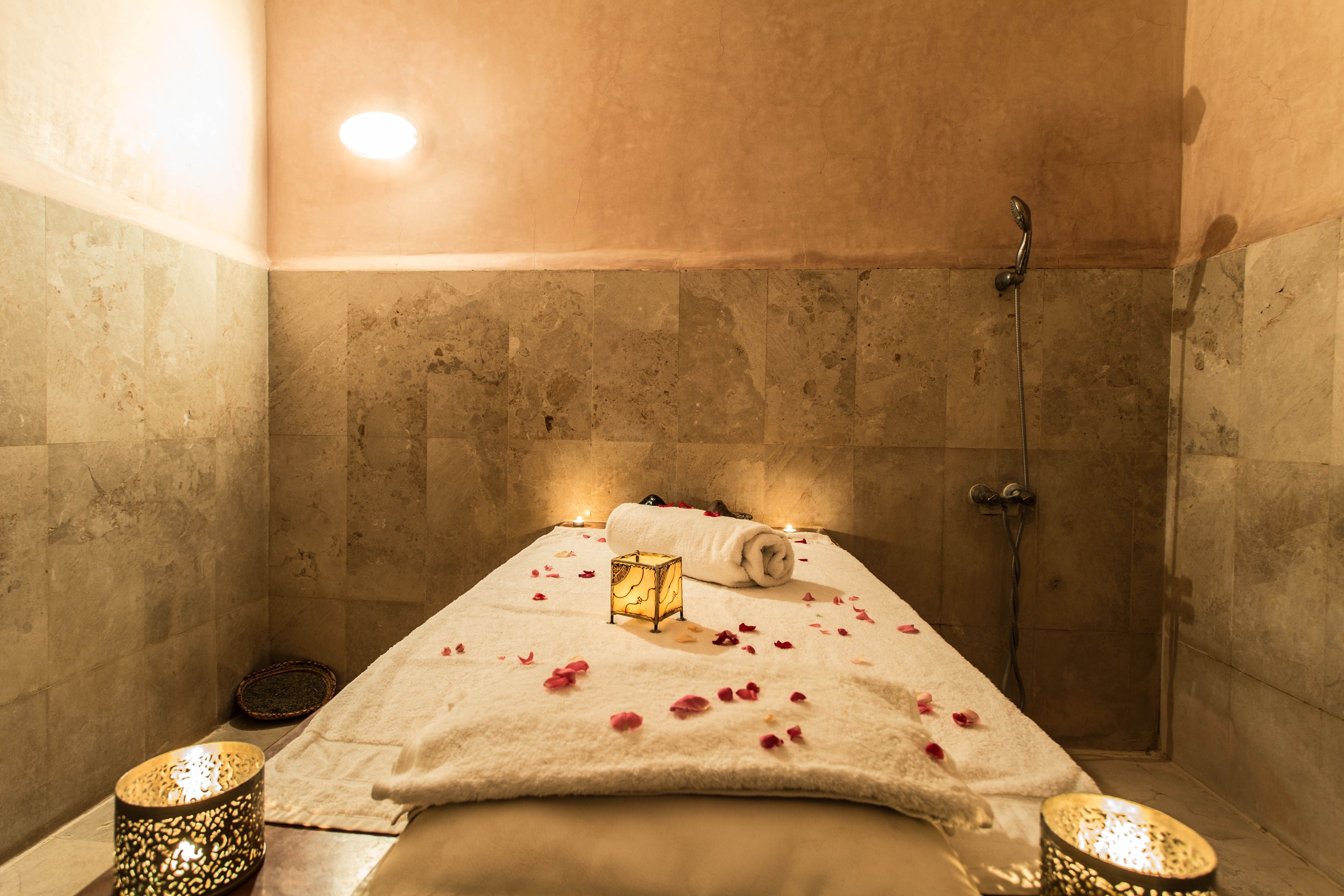A spa room with a bed, a shower, and two candles on either side.