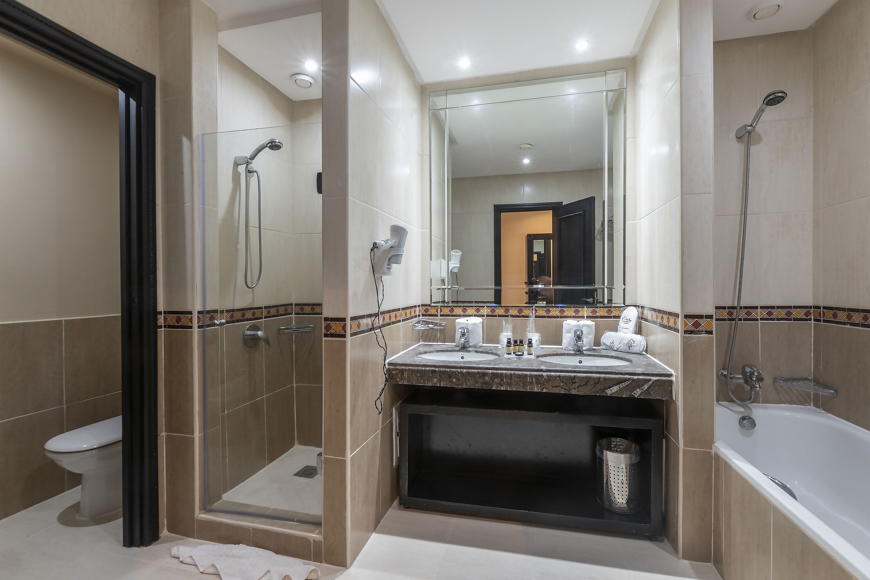 A modern bathroom with a glass-enclosed shower, a bathtub, and a vanity with dual sinks.
