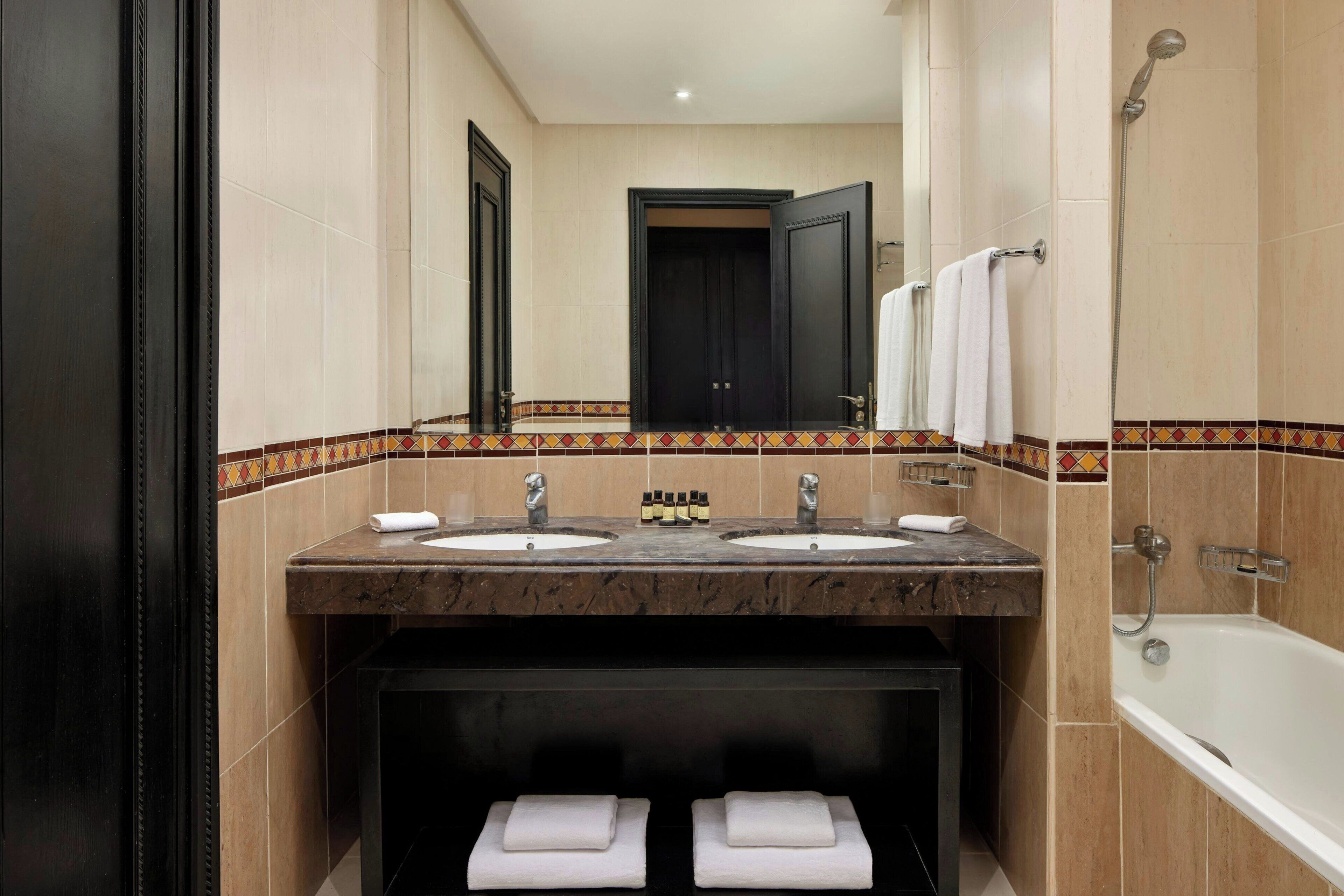 A bathroom with two sinks, a bathtub, and a mirror.