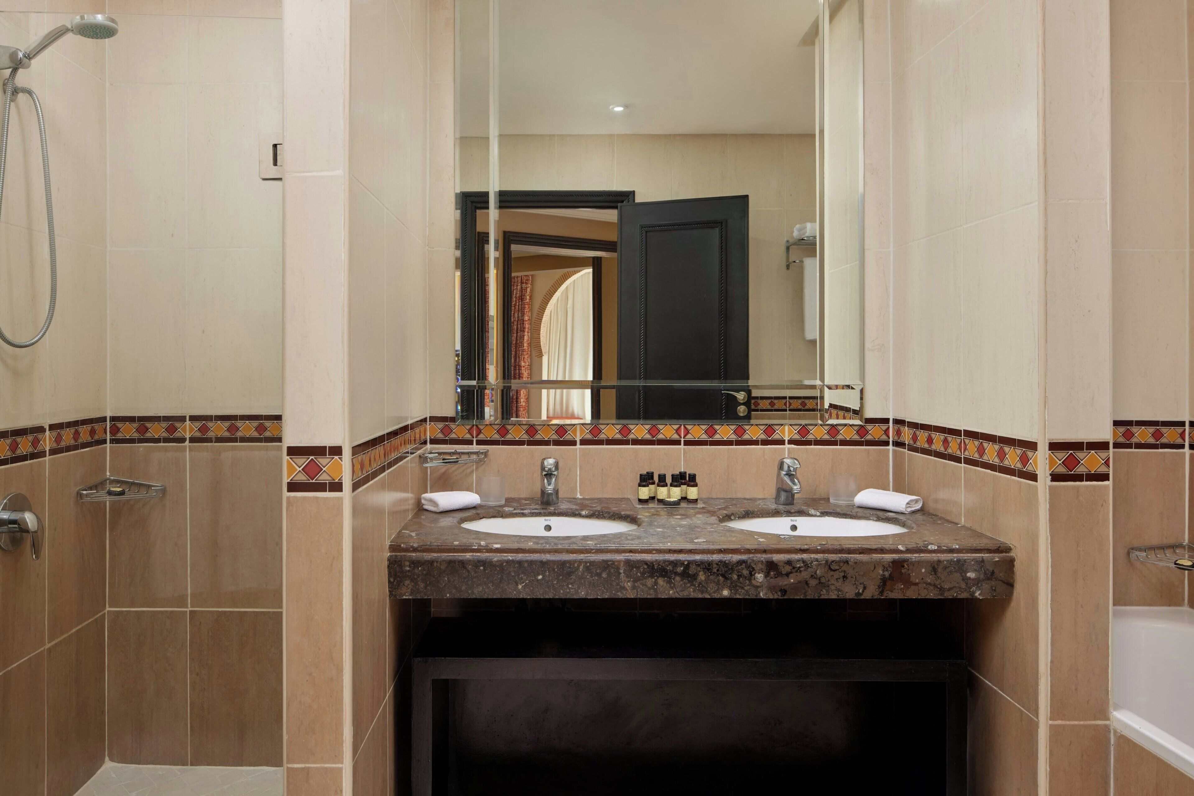 A bathroom with two sinks, a shower, and a mirror.