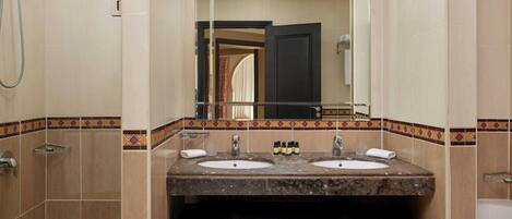 A bathroom with two sinks, a shower, and a mirror.
