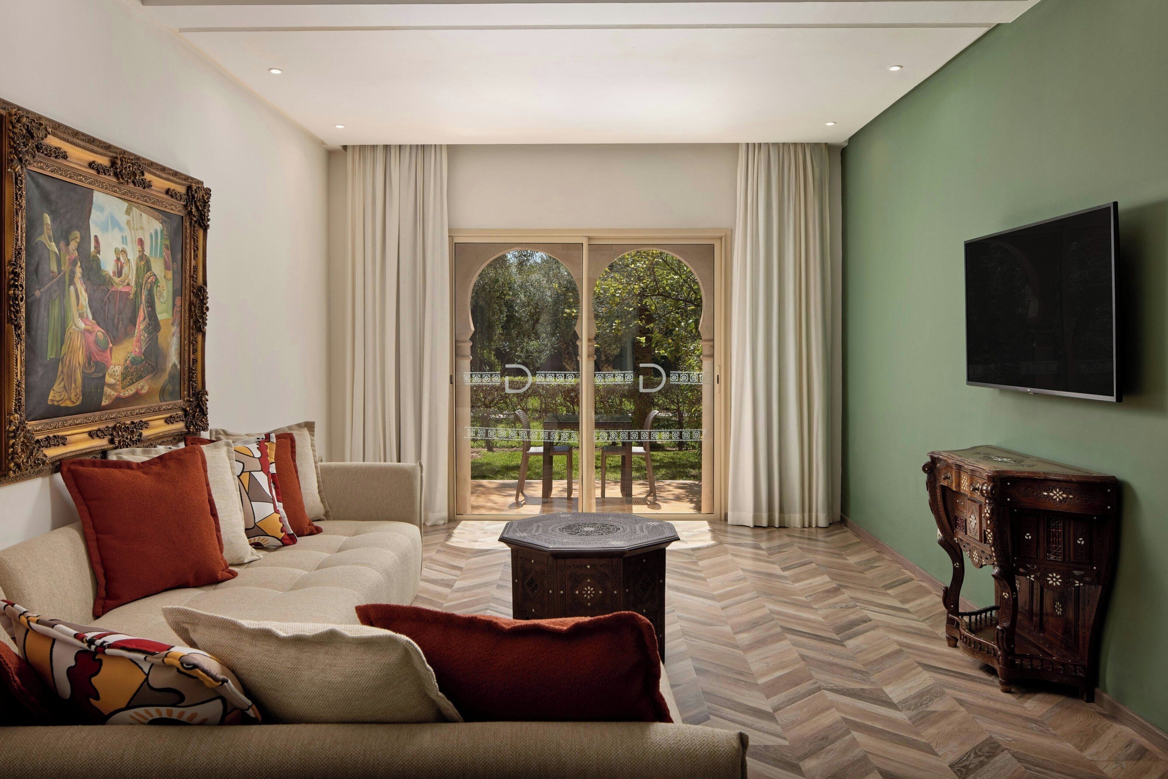 A living room with a sofa, a coffee table, a painting, and a television.