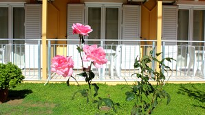 A balcony with white railings and a yellow building facade. - Rantos Apartments (Corfu)