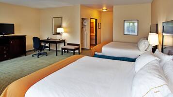 Une chambre d’hôtel avec deux lits, un bureau, une chaise, une télévision et une salle de bain visible à travers une porte ouverte.