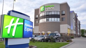 A Holiday Inn Express building with a large illuminated sign, parking area, and a well-maintained lawn. - Holiday Inn Express Waterloo Cedar Falls by IHG (Waterloo)