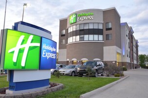 A Holiday Inn Express building with a large illuminated sign, parking area, and a well-maintained lawn.