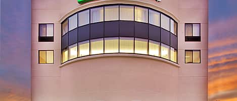 Edificio de Holiday Inn Express con un llamativo logotipo verde y blanco, amplias ventanas y fachada de ladrillo.