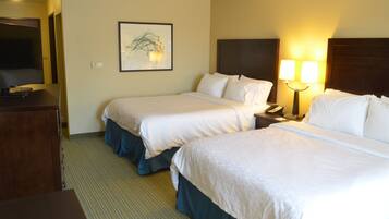 A hotel room with two beds, a television, a framed artwork, and a bedside lamp.