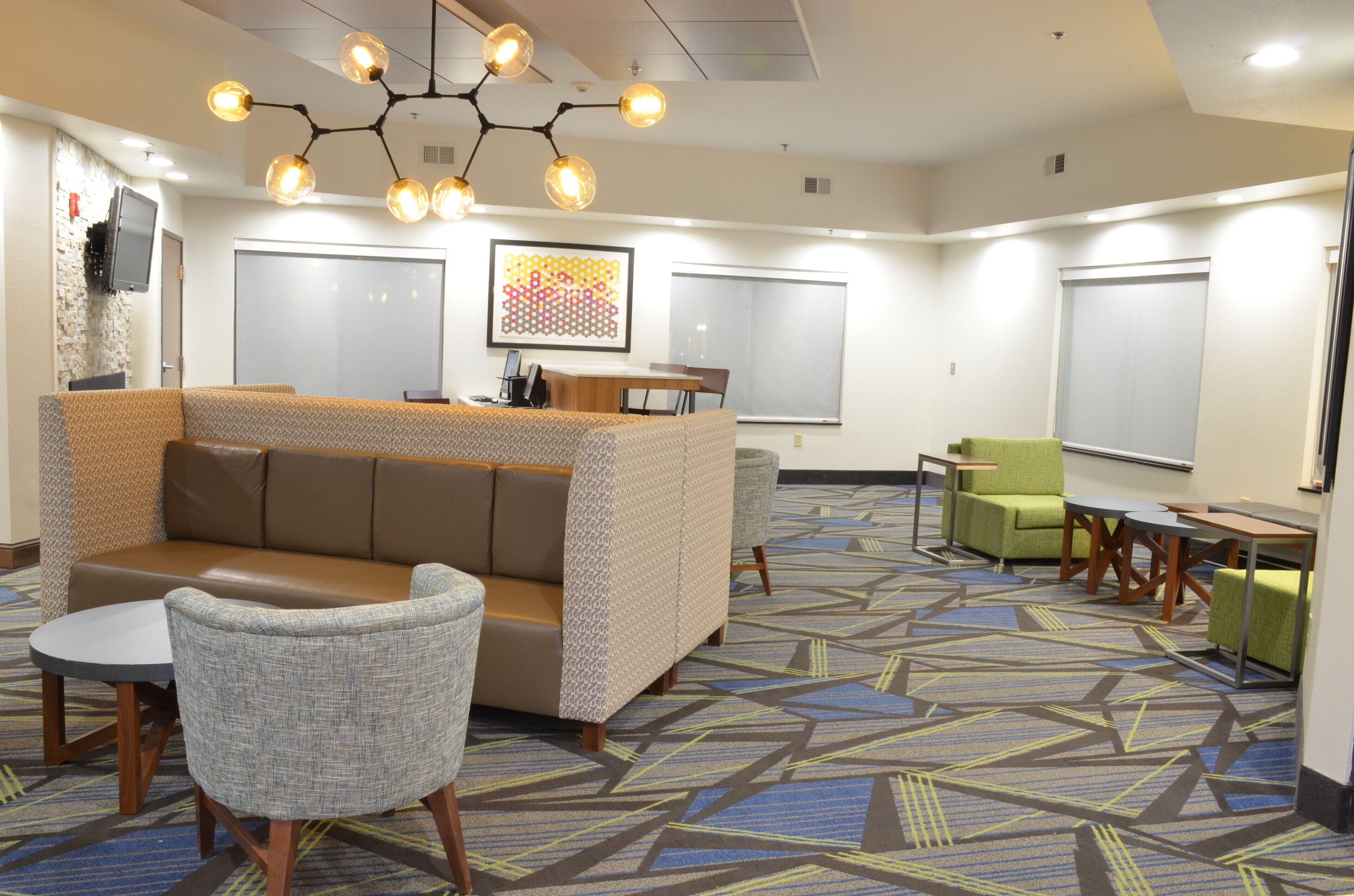 A hotel lobby with a seating area, a reception desk, and a patterned carpet.