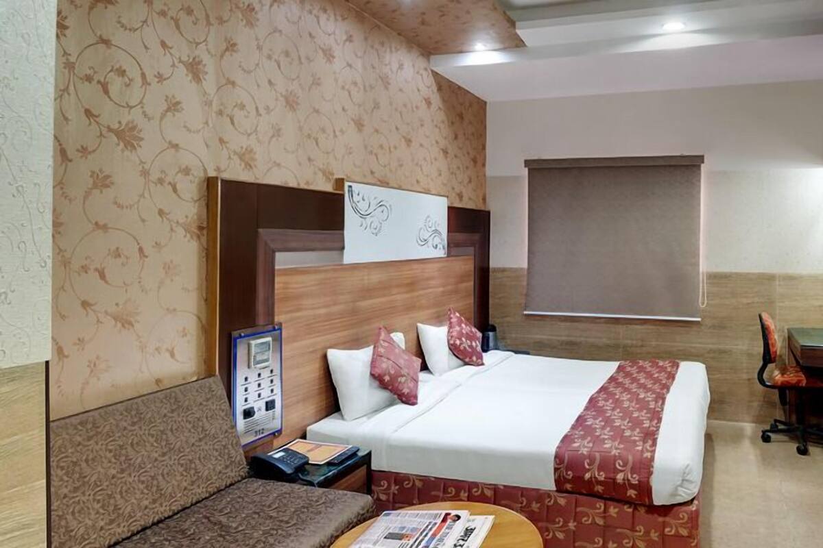 A hotel room with a bed, a desk, a chair, a TV, and a telephone.
