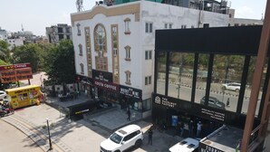 Vista de una calle con un edificio que alberga un hotel, una cafetería y una pastelería.