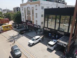 A street view with a building housing a hotel, a coffee shop, and a pastry shop. - Amar Yatri Niwas (Agra)