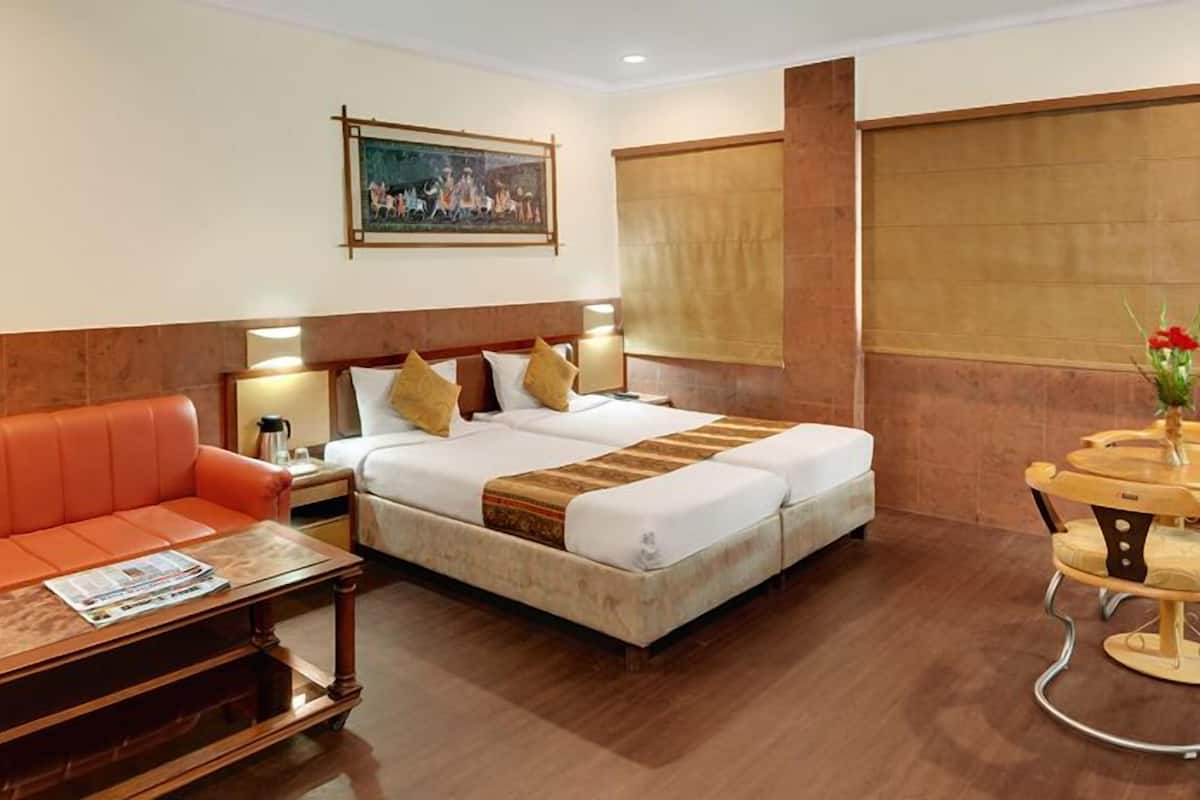 A hotel room with a bed, a sofa, a table, and a chair.