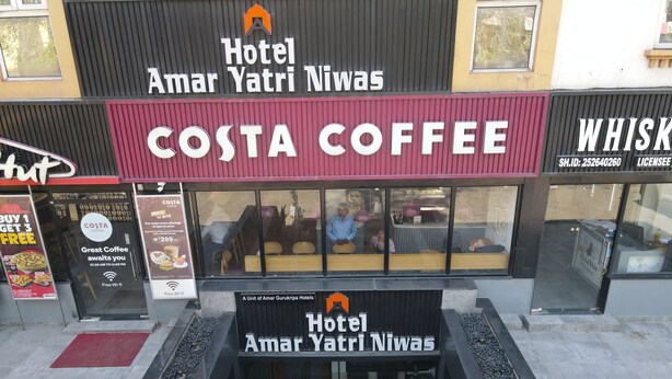 Entrada de hotel con una cafetería Costa Coffee y una tienda de whisky.