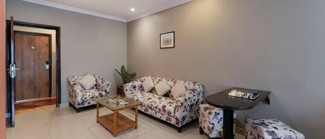 A living room with a sofa set, a coffee table, and a small table with a chess set.
