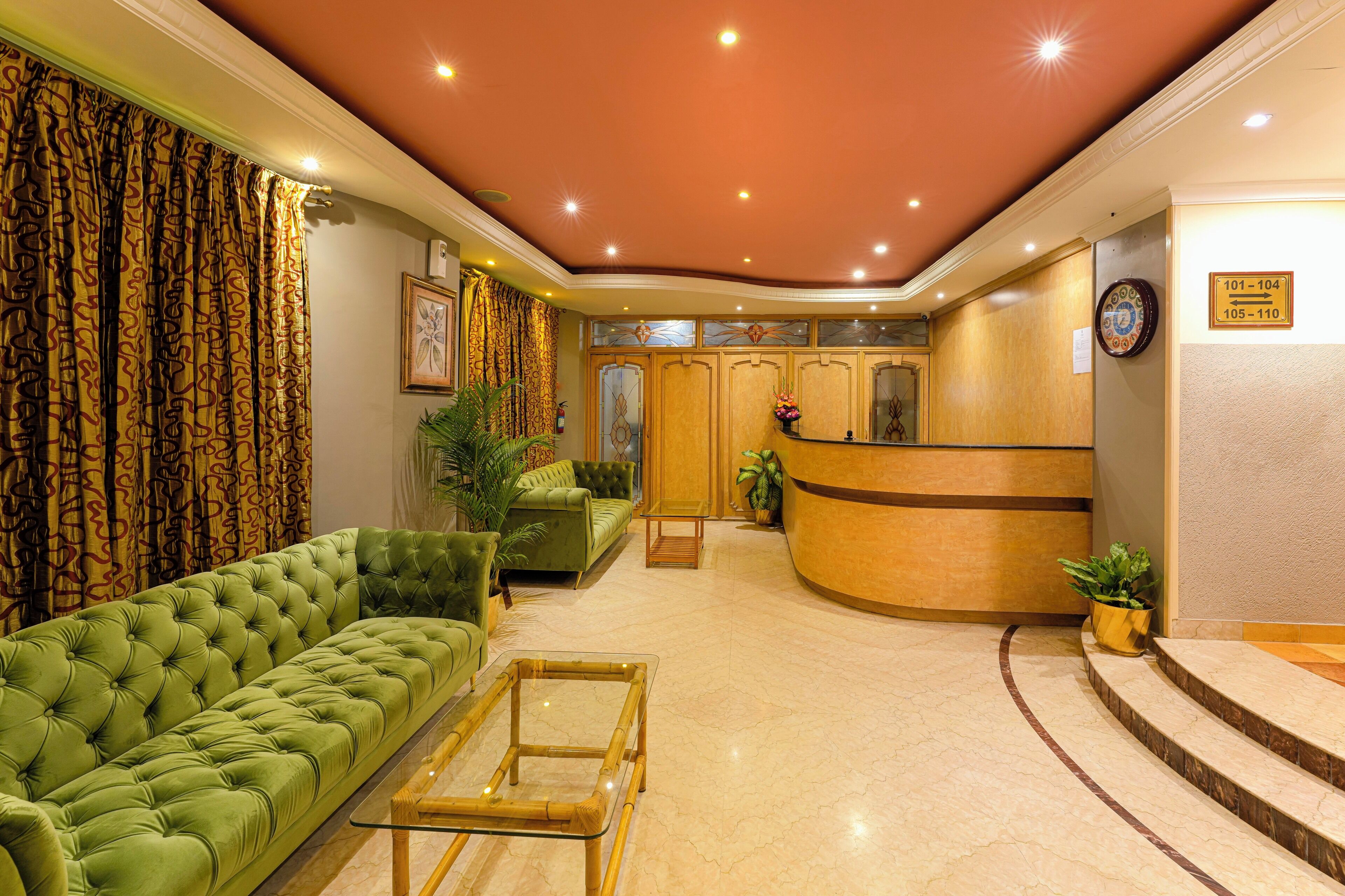A lobby with a green sofa, a reception desk, and a clock on the wall.