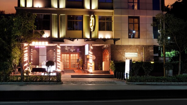 A multi-story hotel with a modern design, featuring a ground-level restaurant and a well-lit entrance. - Cross Roads Inn (Bengaluru)